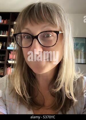 Portrait of blonde woman with glasses making a silly face. Stock Photo