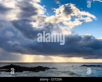 Sunlight streaming through the clouds over the ocean Stock Photo