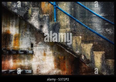 Weathered concrete staircase with blue banister Stock Photo
