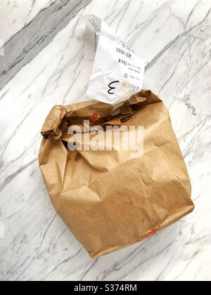 Bag of take out on a marble counter top in kitchen at home, from an online web order and contactless pick up Stock Photo