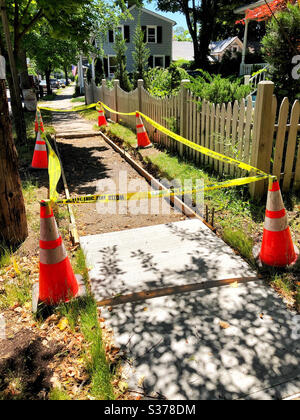 Construction site for building a cement or concrete sidewalk. Site has been leveled, wood frame installed, and has been checked for underground electric wires. Marked with yellow safety tape, cones Stock Photo