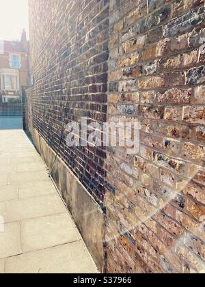 Brick wall and pavement in a Victorian terraced street of Stoke Newington, north London, UK Stock Photo