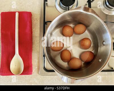 Closeup view of free range organic farm eggs in a pan of boiling water. Preparing hard boiled eggs on the stovetop. Gently simmering over gas stove. Stock Photo