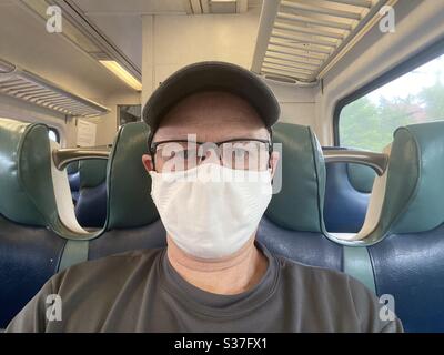 Lone senior man wearing face mask, on commuter train during covid-19 pandemic Lockdown in New York City. Stock Photo