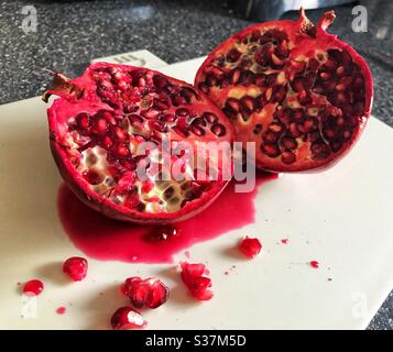 Pomegranate cut open on a chopping board Stock Photo