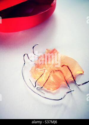 Still life of a Hawley now retainer dental appliance on a bathroom sink with storage case Stock Photo