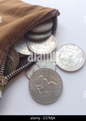 A zippered bag filled with vintage silver dollars close up