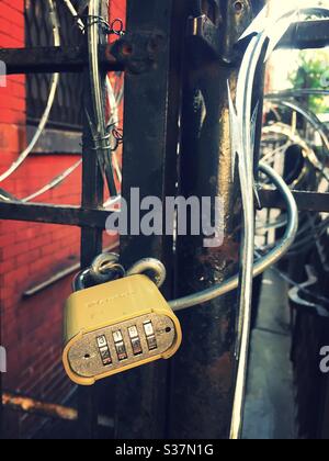 Combination lock on a street side gate with razor wire, NYC, USA Stock Photo