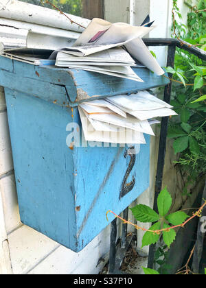 Mail overflowing mail box or post box at abandoned house Stock Photo