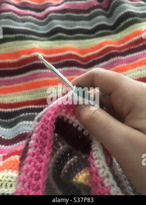 Hand holding a crochet hook making a blanket Stock Photo