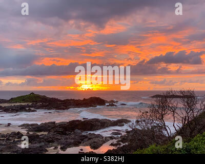 Illuminated. Sunrise by the sea with orange and pink reflected in the water Stock Photo