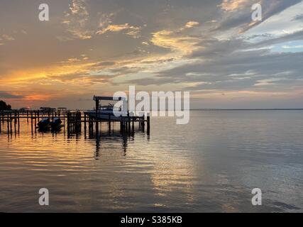 Colorful sunset skies over bay water with boat dock and reflections on the water Stock Photo