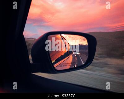 Flaming sunset reflecting in side view mirror of the car on the way from Death Valley National  Park in California Stock Photo
