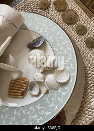 Seashells and sand dollars lying on a decorative table set Stock Photo