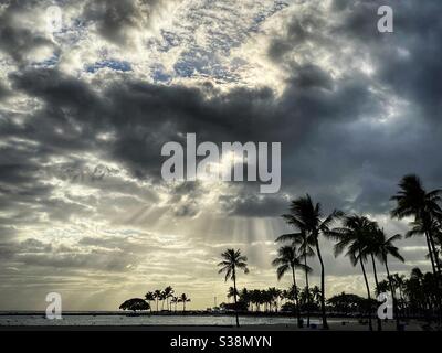 Sunlight streaming through clouds in a tropical landscape Stock Photo