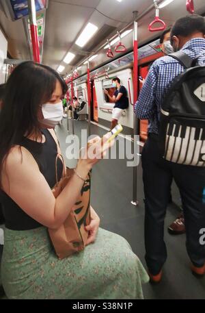 A woman wearing a protective mask using her smartphone. Stock Photo