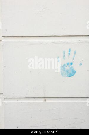 Blue handprint on a cream wall Stock Photo