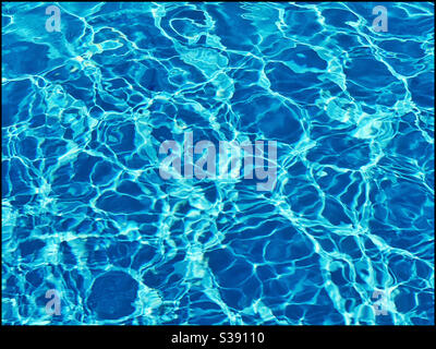 Water in a swimming pool ripples due to bright sunshine. A mysterious but interesting image of clear “blue” water. Photo Credit - ©️ COLIN HOSKINS. Stock Photo