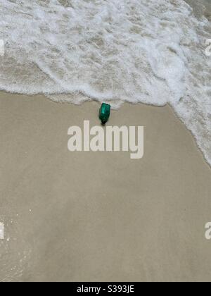 Looking down on a green glass bottle washed ashore on the beach Stock Photo