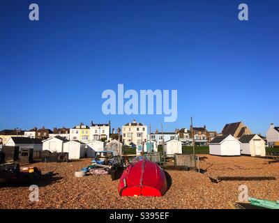 Red fishing boat moored upside down on the beach at Walmer Deal UK Stock Photo