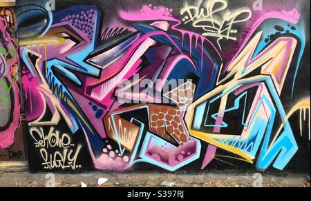 Stylised graffiti purple and pink on stone wall in Brighton UK Stock Photo