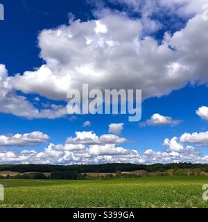 Cumulus clouds in blue sky over central France farmed landscape. Stock Photo