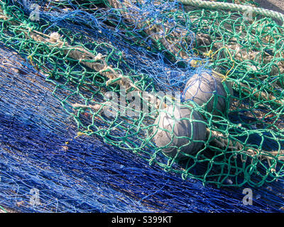 green blue fishing net with floating buoys and thick white ropes lying at  the harbour to dry in the sun Stock Photo - Alamy