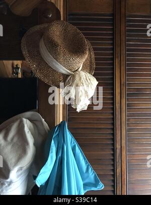 Two hats and a jacket hanging in entryway on antique hall tree illuminated with natural light from window Stock Photo