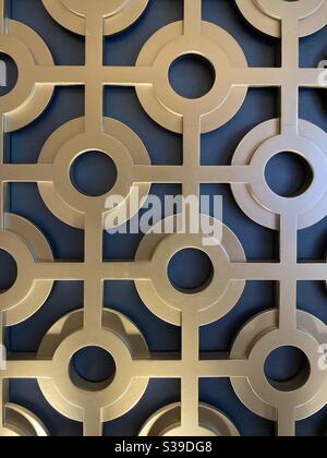Metal round disc patterns on a blue wall background Stock Photo