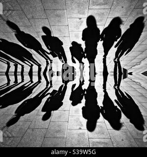 Mirror effect of group of people shadows walking on the street. Stock Photo