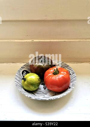 Three different kinds of tomatoes in a vintage ceramic bowl Stock Photo