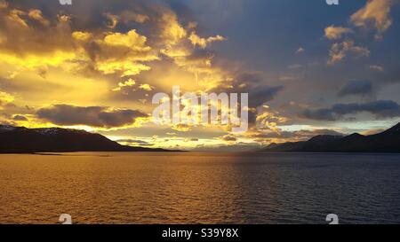 Dramatic sunset at sea with golden sky and clouds Stock Photo