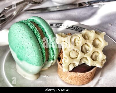 Apple Macaron and A Chocolate Tart on a Plate at Carriages Of Cambridge Afternoon Tea Stock Photo