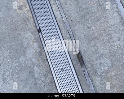 Metal drain cover and concrete creating abstract grunge background, suitable for compositing with text and graphics Stock Photo