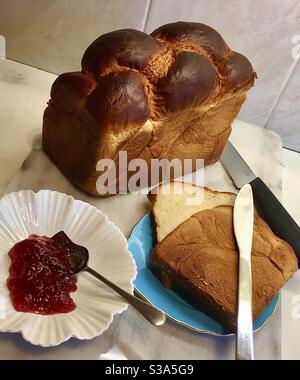 Freshly-baked French Brioche loaf cut into slices ready for strawberry jam. Enriched pastry made with eggs and butter, Brioche is like a cross between pastry and bread and dates from the 1400s. Stock Photo