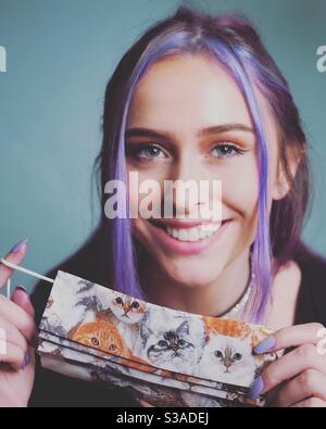 Beautiful young woman holding up handmade cotton face mask, Covid prevention Stock Photo