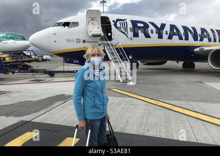 Travel in covid 19 restrictions, masked passenger waiting to board a Ryanair plane at Dublin airport with Aer Lingus plane in background Stock Photo