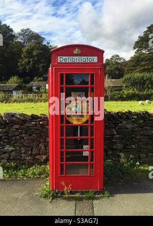 A red British telephone box that has been converted into a defibrillator station in the UK countryside for public use Stock Photo