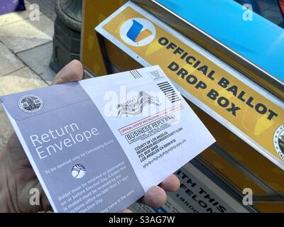 LOS ANGELES, CA, OCT 2020: hand about to place 2020 US presidential election voting form in return envelope into an official ballot drop box in Downtown Stock Photo