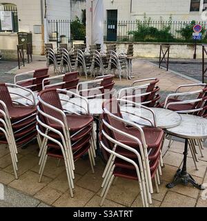 Stacked café chairs and tables due to closed business during Covid-19 lockdown in France. Stock Photo