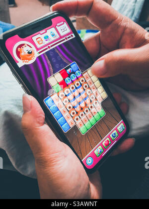A lady plays a game on her smartphone. Stock Photo