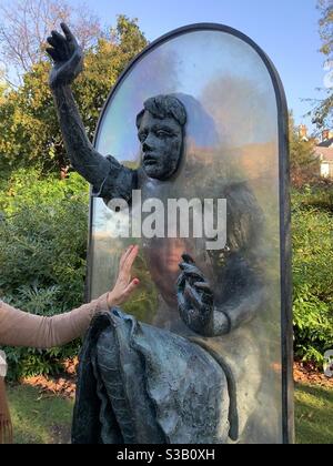 Woman’s face reflected in Alice through the looking glass statue Guildford Stock Photo