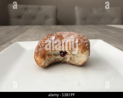 Half eaten jam doughnut on a white plate Stock Photo