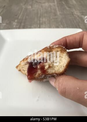 Lady holding a half eaten jam doughnut in her hand Stock Photo