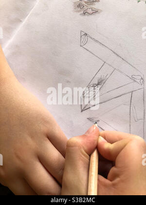 Close up of a child’s hands doing a drawing in pencil on white paper. Stock Photo