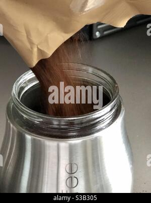 Ground coffee being poured into a storage jar Stock Photo