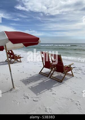 Colorful red lounge chairs and outdoor umbrella on white sand Florida beach Stock Photo