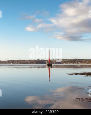 thin red sail in Carrick Roads Stock Photo
