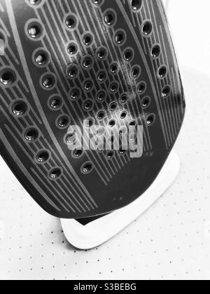 Graphic, high contrast black and white still life of underside of steam iron from above against a very light background. Stock Photo