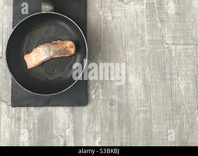 Fillet of salmon in a pan on a wooden background Stock Photo